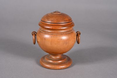 a small wooden urn with a lid on a table