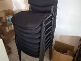 une pile de chaises noires dans un coin de la pièce