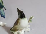 a small figurine of a bird and a bird on a branch