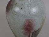 a white vase with a red spot on it