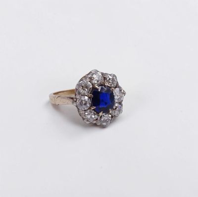a close up of a blue and white diamond ring on a white surface
