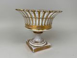 un vase blanc et or sur un support posé sur une table