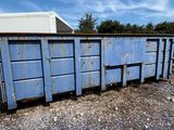 une benne bleue posée au milieu d'un terrain en gravier