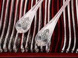 several silver spoons and forks in a red case on a table