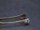 pair of silver spoons on a black surface with a black background