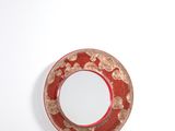 une assiette rouge ornée d'un motif circulaire sur un fond blanc