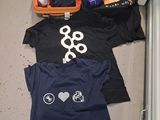trois t-shirts par terre, à côté d'une valise ouverte