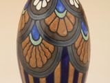 un vase bleu et brun posé sur une surface blanche