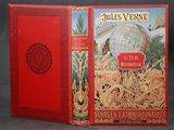 an old book with a red cover sitting on top of a table