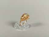 une image représentant une bague en or sertie d'un diamant, posée sur un socle transparent