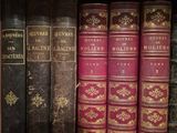 several old books are lined up on a shelf in a library
