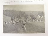 a black and white photo of a group of people riding horses and dogs