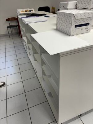 Des cartons sont empilés sur un bureau blanc dans une pièce