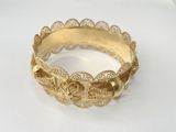 an image of a close up of a gold bracelet on a white surface
