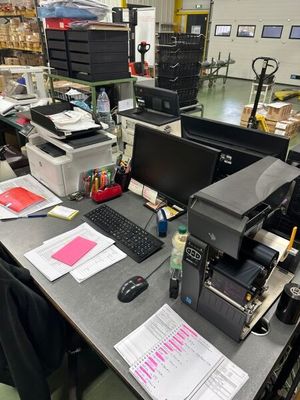 un bureau sur lequel se trouvent un ordinateur, une imprimante et d'autres objets