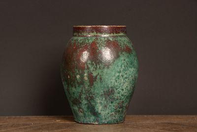 a green vase sitting on a table with a black background