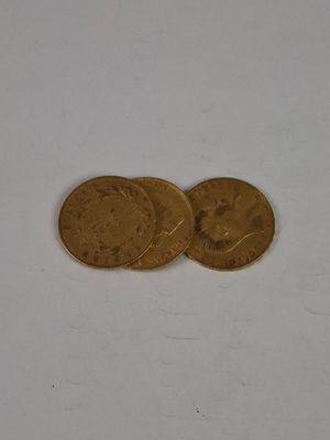two gold coins sitting on top of each other on a white surface