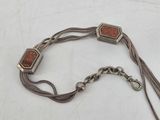 an image of a silver chain bracelet with a red stone on it