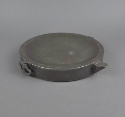 une assiette en argent avec une poignée, posée sur un fond blanc