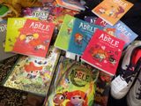 many children ' s books on a bed with a pair of shoes