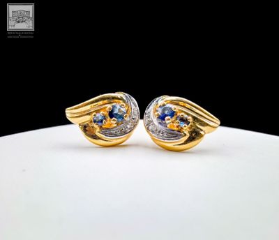 une paire de boucles d'oreilles en or et saphir bleu sur un fond blanc