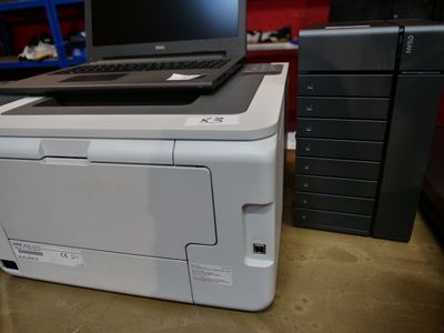 un ordinateur portable posé sur une imprimante, sur un bureau