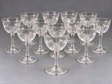 twelve clear wine glasses lined up in a row on a gray surface