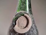 a green bottle with a hole in it sitting on a table