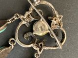 a silver brooch with a heart and two spoons on it
