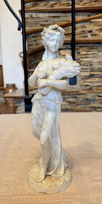 a white statue of a woman holding a baby on a table
