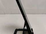 a small black cell phone on a stand on a white surface