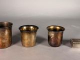 three silver cups and a book are sitting on a table