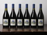 six bottles of wine sit on a table in front of a wall