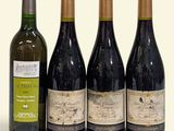 trois bouteilles de vin sont posées les unes à côté des autres sur une surface blanche