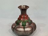 un vase en argent orné d'un motif rouge et vert