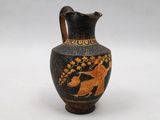 a black vase with a painting on it sitting on a table