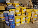 many buckets of paint sitting on the floor in the garage