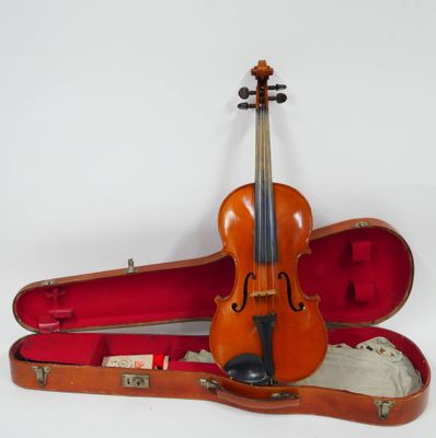 un vieux violon repose dans son étui, posé sur une surface blanche