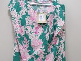 a green top with pink flowers on it hanging on a hanger