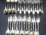 twelve silverplated spoons and forks arranged on a black surface