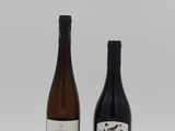 two bottles of wine sitting next to each other on a white surface