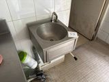 un lavabo dans un coin d'une salle de bains où le sol est encombré d'objets