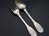 two silver spoons and a fork on a black background