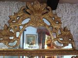a mirror with a gold frame and a picture on the wall