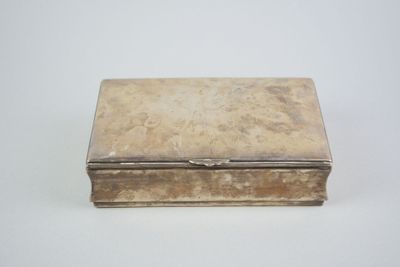 une vieille boîte en argent posée sur une table blanche