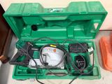une boîte à outils verte posée par terre, contenant des outils