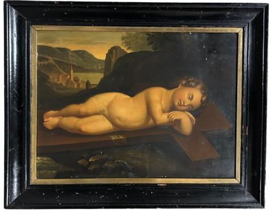 un vieux tableau représentant un bébé allongé sur une croix, dans un cadre noir