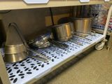 several pots and pans are on a shelf in a kitchen