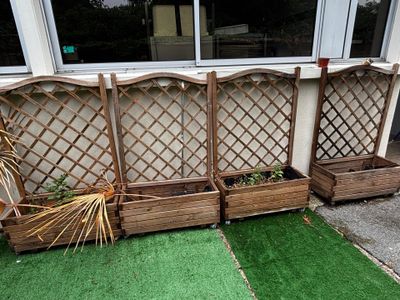trois jardinières en bois contenant des plantes, posées sur l'herbe