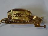 a gold plated brooch with a clock on it